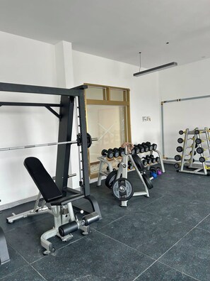 A gym with weightlifting equipment, benches, and dumbbells. - Traveler's Loft- Park views near JKIA&SGR with Pool & Gym (Nairobi)