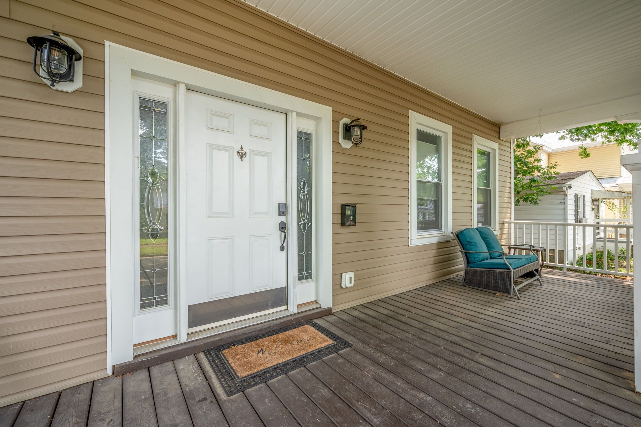 A wooden porch with a white door, a bench, and a small table.