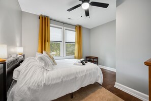 A bedroom with a bed, a nightstand, a lamp, a ceiling fan, and a window with curtains. - Spacious 3 BR Home with Fire Pit & Fenced Backyard - Pet Friendly (Richmond)