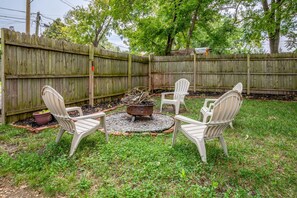 A backyard with a fire pit, four Adirondack chairs, a potted plant, and a wooden fence. - Spacious 3 BR Home with Fire Pit & Fenced Backyard - Pet Friendly (Richmond)