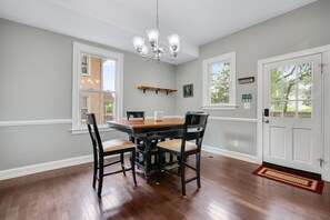 A dining room with a wooden table and chairs, a chandelier, and a door with a window. - Spacious 3 BR Home with Fire Pit & Fenced Backyard - Pet Friendly (Richmond)