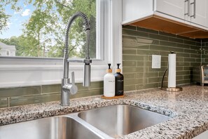 A kitchen with a stainless steel sink, a modern faucet, and two soap dispensers on the countertop. - Spacious 3 BR Home with Fire Pit & Fenced Backyard - Pet Friendly (Richmond)