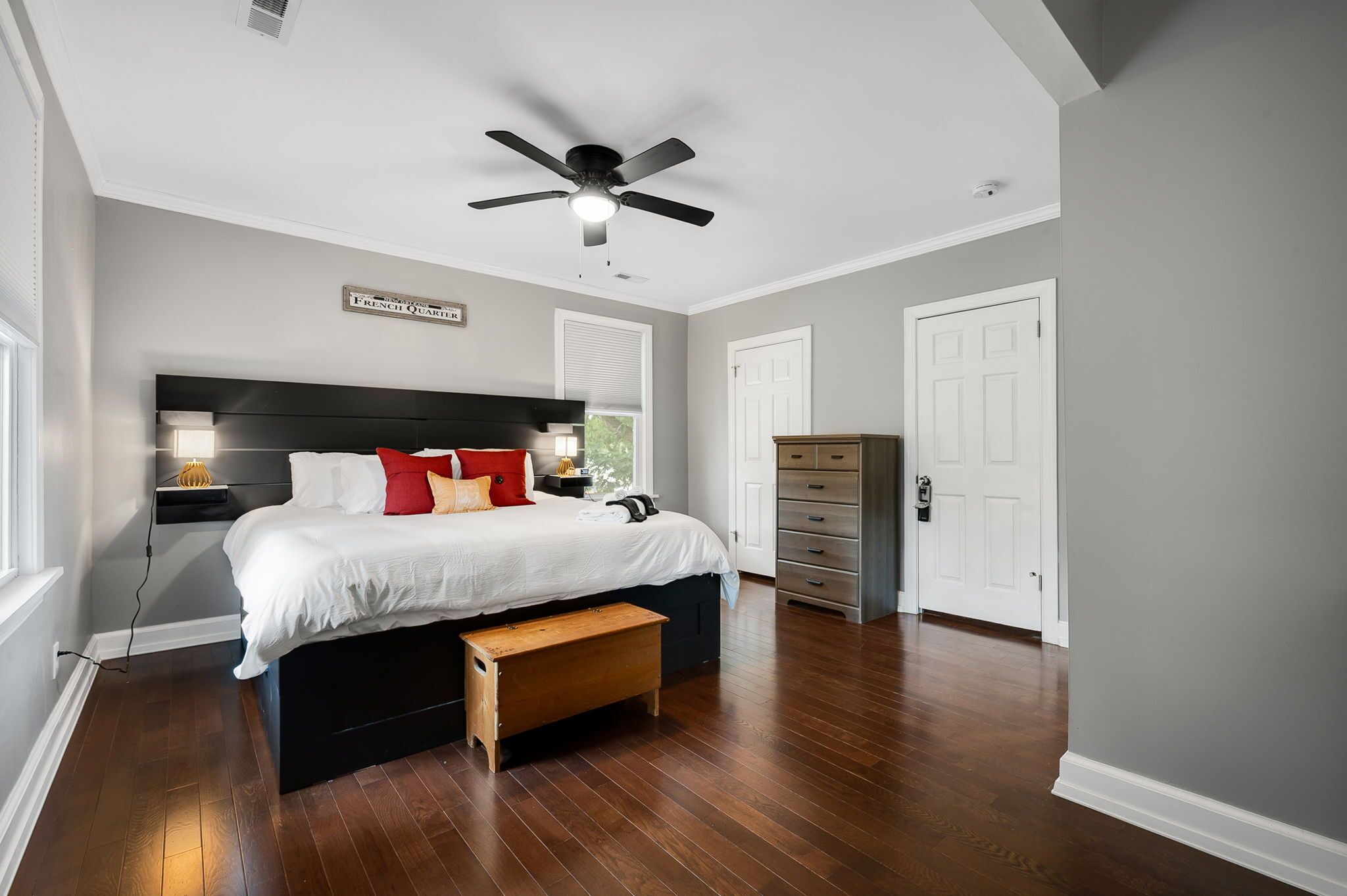 Une chambre à coucher avec un lit, une table de chevet, une lampe et un ventilateur de plafond.