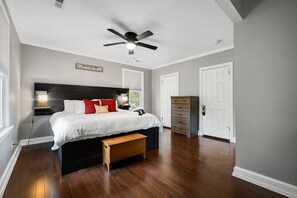 A bedroom with a bed, bedside table, lamp, and a ceiling fan.