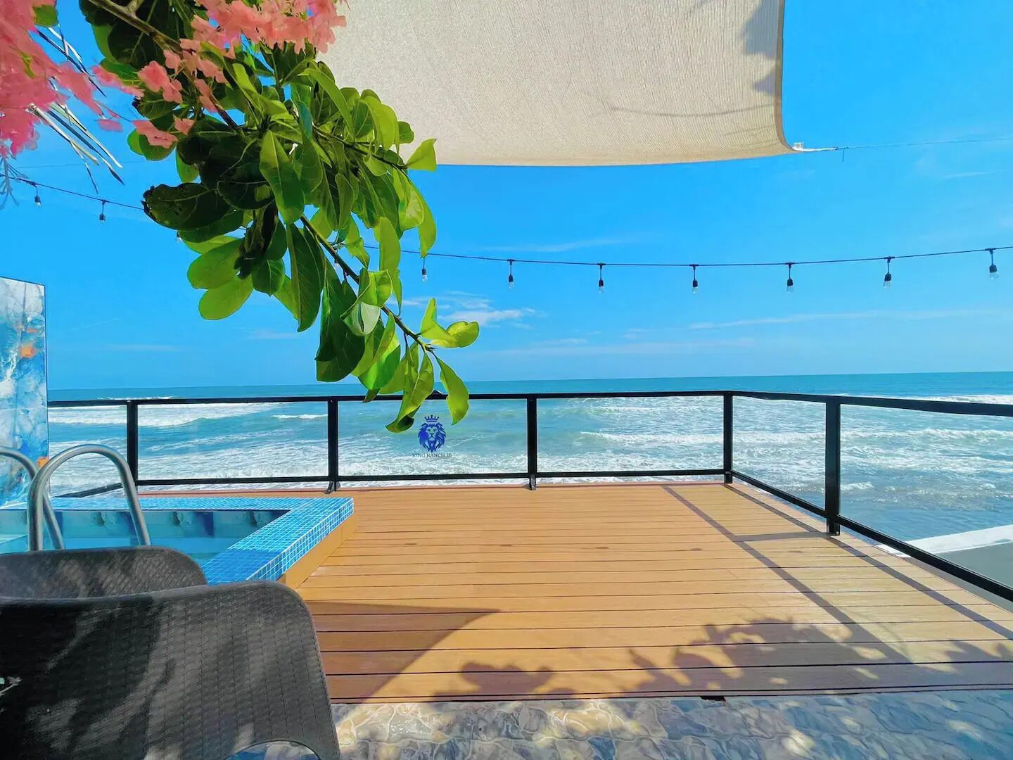 Une terrasse en bois avec une piscine, offrant une vue sur l’océan.