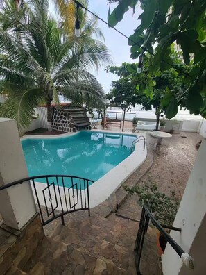 A swimming pool with a stone-tiled deck, surrounded by palm trees and potted plants. - JB King Ranch Beach House (La Libertad)