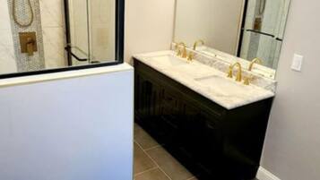 A modern bathroom with a toilet, a vanity with a mirror, and a shower area.