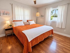 A bedroom with a large bed, a bedside table with a lamp, and a window with curtains. - Clearwater Oasis | Private Pool | 5mi from Beach (Pinellas County)