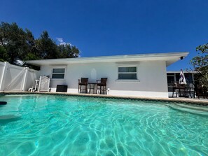 Una casa con piscina, patio cercado y cielo azul despejado.