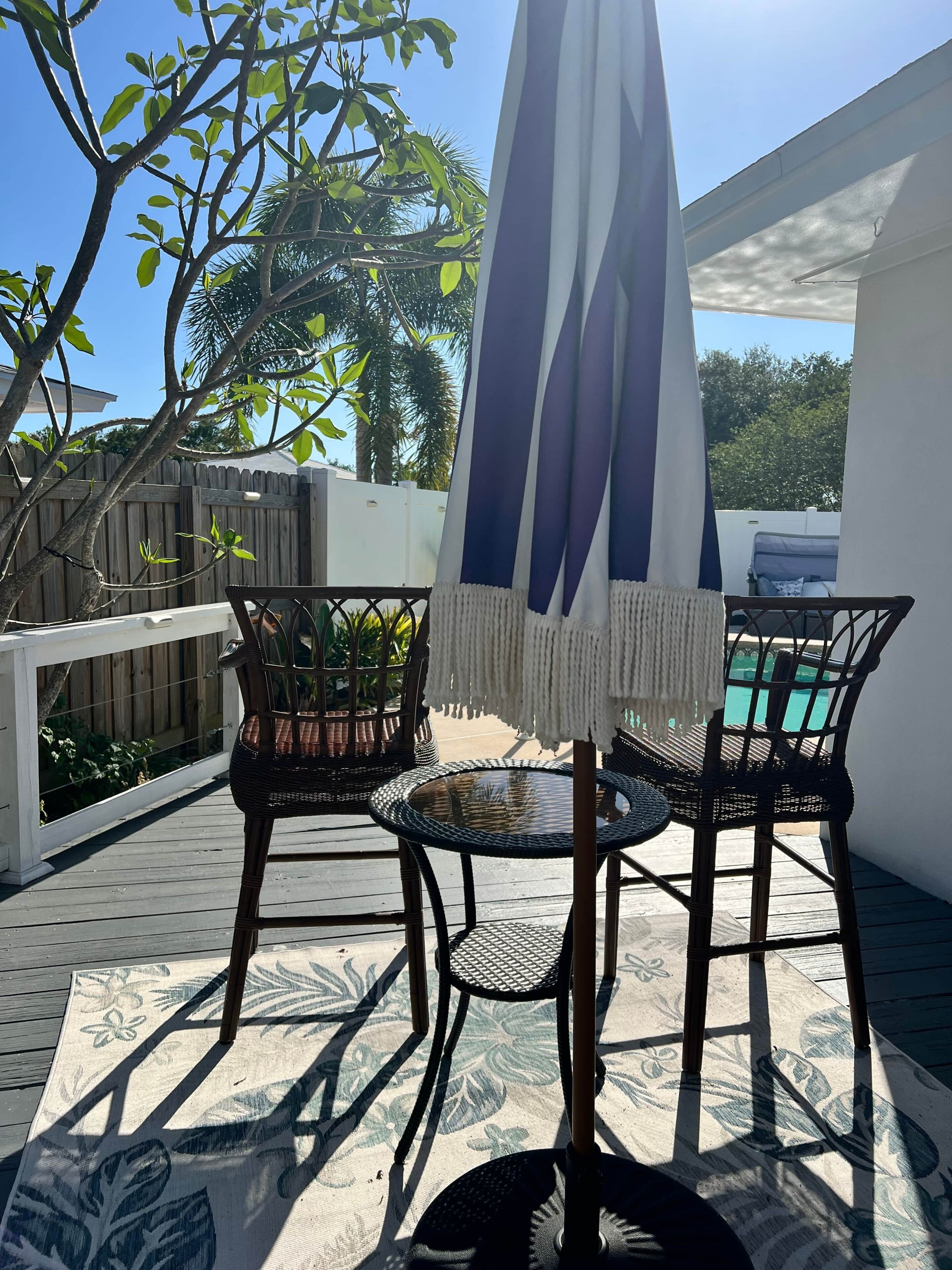 Eine Terrasse im Freien mit Korbmöbeln, einem Pool und einem Holzboden.