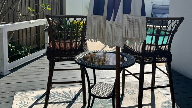 Eine Terrasse im Freien mit Korbmöbeln, einem Pool und einem Holzboden.
