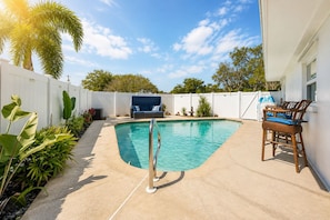 A swimming pool with a white fence, a lounge chair, and a small table. - Clearwater Oasis | Private Pool | 5mi from Beach (Pinellas County)