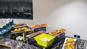 A buffet setup with various food items and serving utensils. - Oz Park Hotel (Al Qunfudhah)
