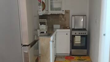 A kitchen with a refrigerator, oven, and cabinets.