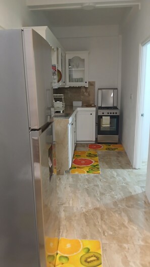 Eine Küche mit Kühlschrank, Backofen und Schränken.