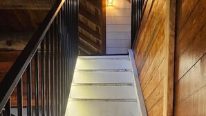 Un escalier en bois avec une rampe en métal, qui monte.