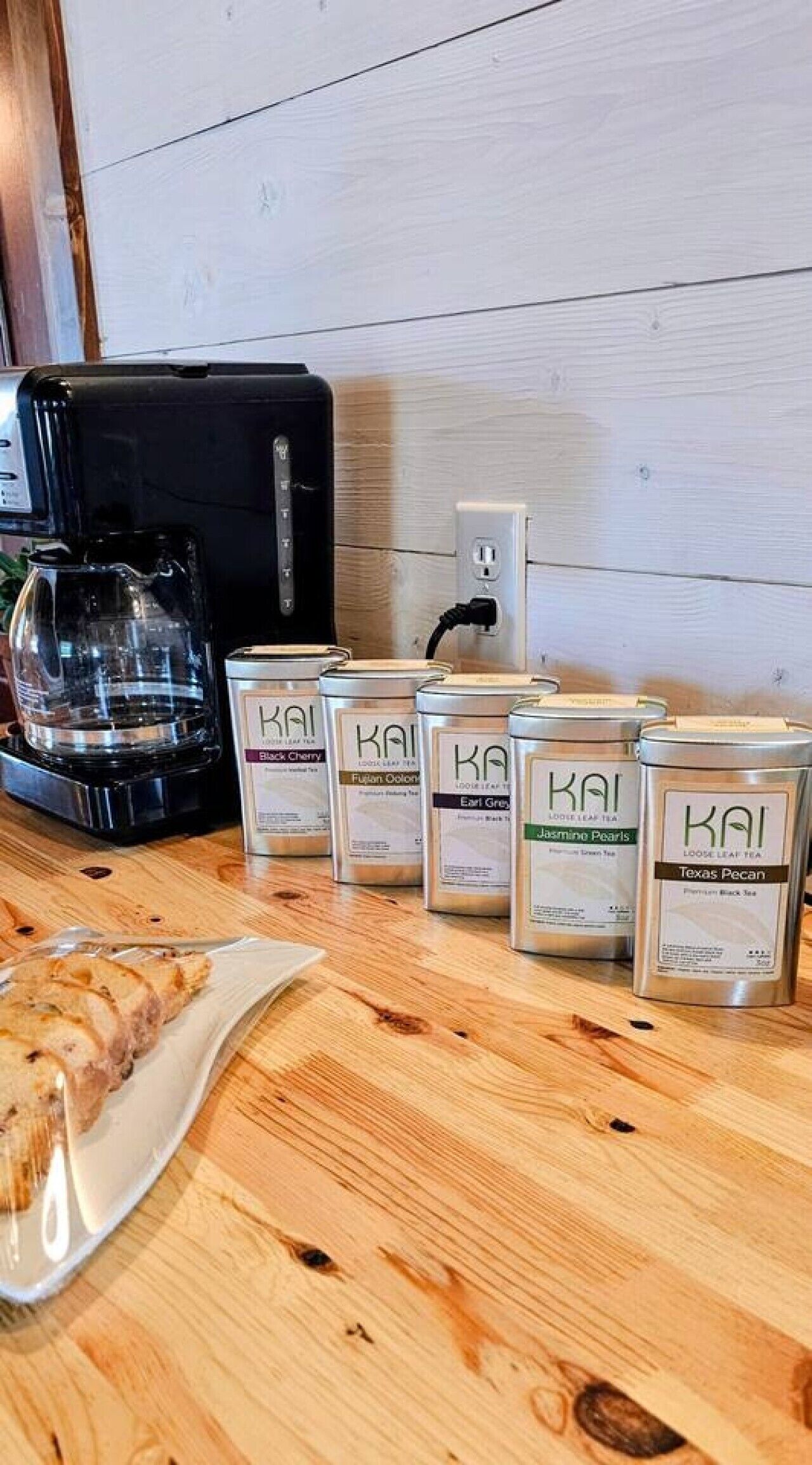 Eine Küchenarbeitsplatte mit einer Kaffeemaschine, einem Teller mit Essen und mehreren Teebeuteln.