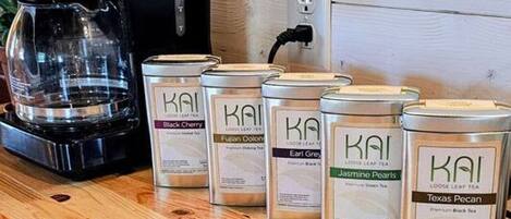 Eine Küchenarbeitsplatte mit einer Kaffeemaschine, einem Teller mit Essen und mehreren Teebeuteln.