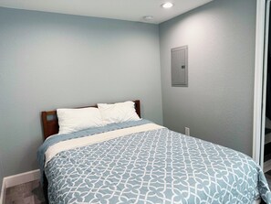 A bedroom with a bed, a wall-mounted light, and a door. - Huge Yard Pet Friendly 2-bedroom Garden Level Private Suite with Kitchen (Thornton)
