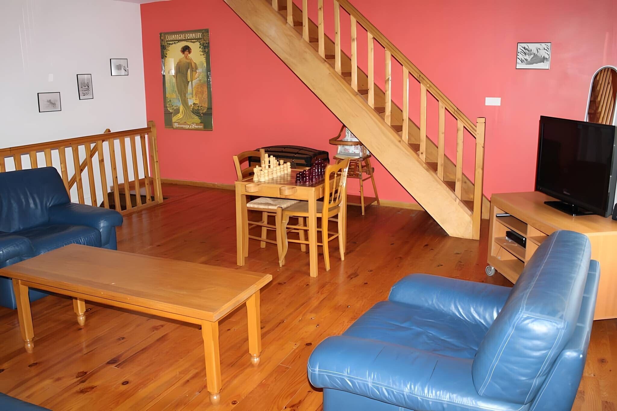 Un soggiorno con una scala in legno, un televisore, un tavolino da caffè e divani in pelle blu.