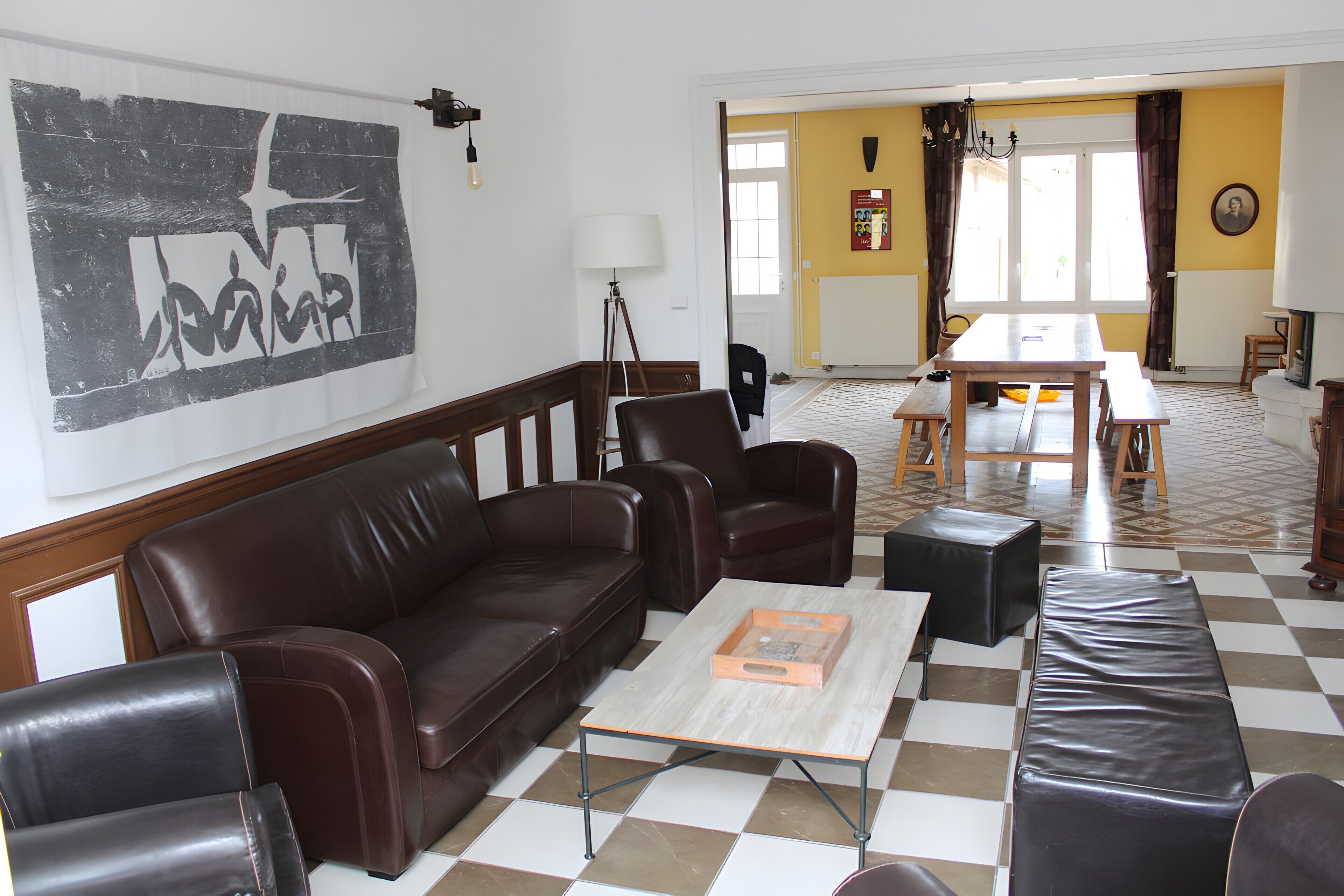 Un salon avec un canapé en cuir marron, une table basse et un coin repas comprenant une table et des chaises.