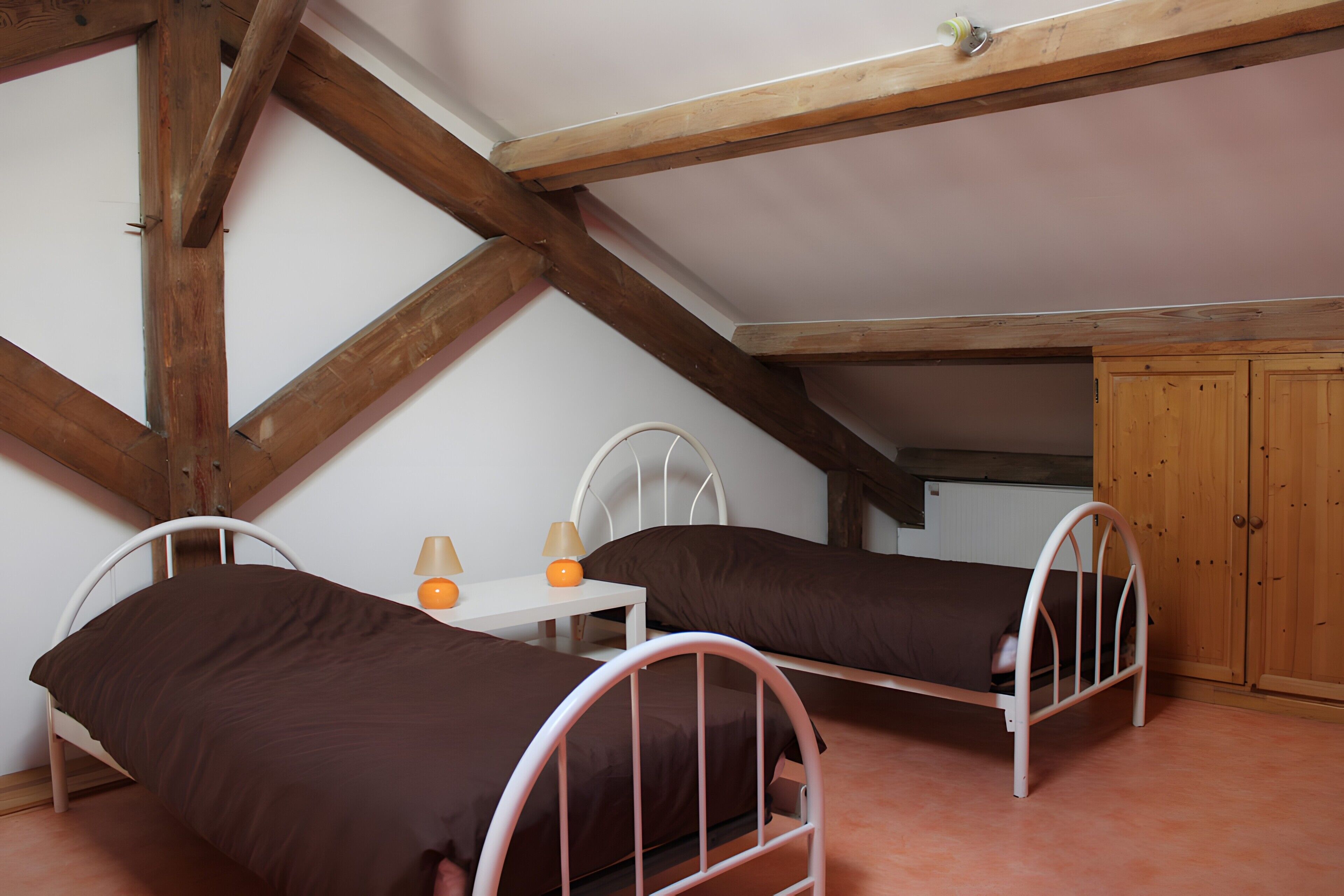 Een slaapkamer met twee metalen stapelbedden, een klein nachtkastje met een lamp en een houten garderobe.