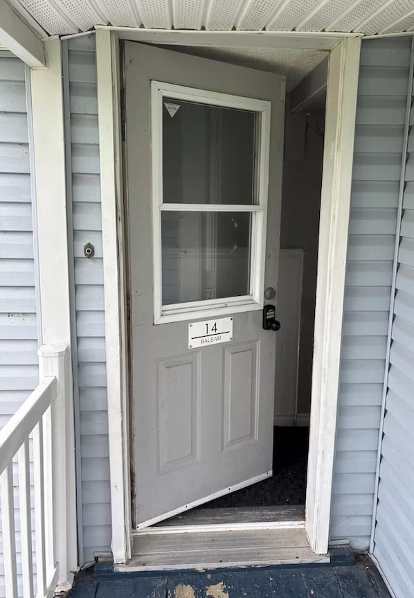 A grey door with a window and a doorbell, marked with the number 14.