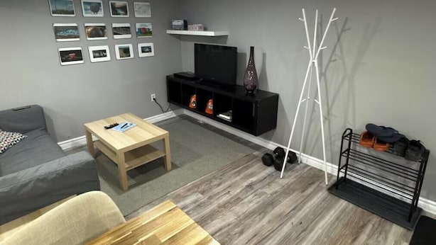 Ein modernes Wohnzimmer mit einer Couch, einem Couchtisch, einer TV-Konsole und Wanddekorationen.