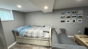 Ein gemütliches Schlafzimmer mit einem Bett, einer Couch, einem kleinen Tisch und einer Wand mit gerahmten Bildern.