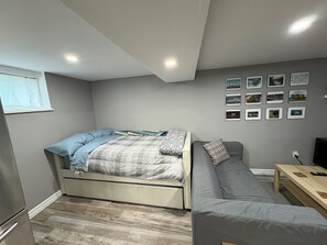 Une chambre à coucher de taille modeste, comprenant un lit, un canapé, une petite table et un mur orné de tableaux.