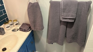 Ein Badezimmer mit Waschbecken, Spiegel und Handtüchern an einem Haken.