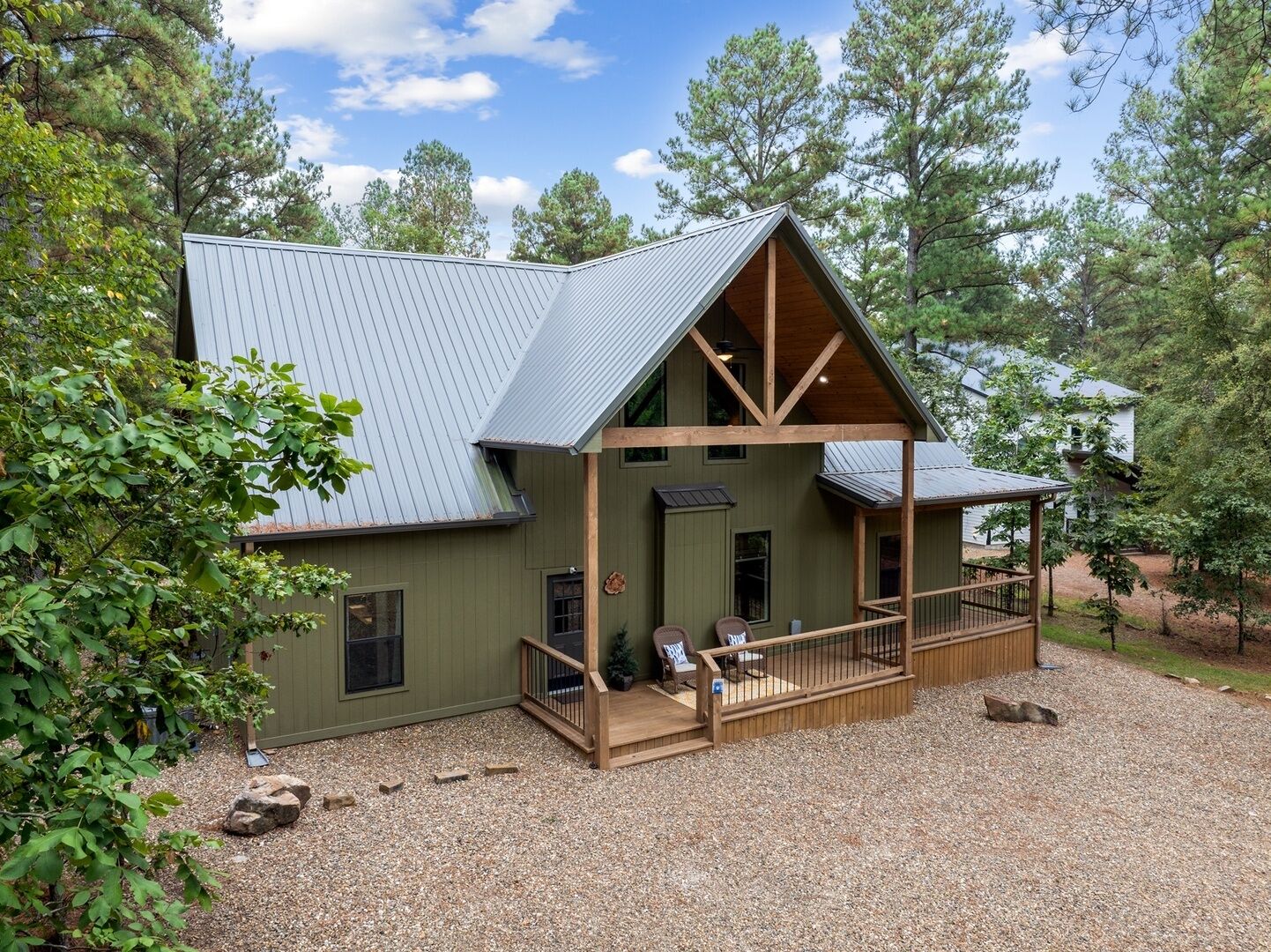 A two-story cabin with a porch, surrounded by trees.