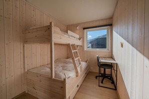 A bunk bed with a ladder, a desk, and a chair in a room with wooden walls and a window. - Spacious Apartment in city centre (Hol)