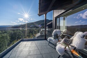A balcony with a view of a mountainous landscape and a body of water.