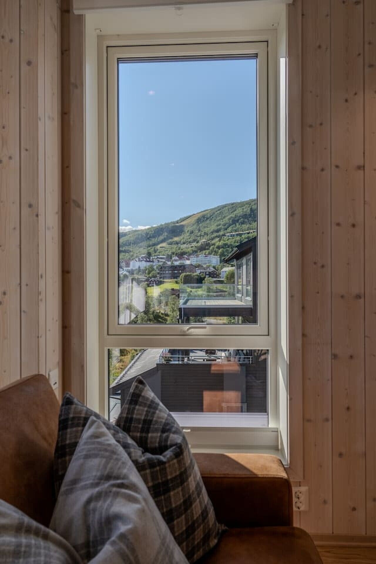 A room with a large window offering a view of a hillside and buildings.