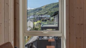 A room with a large window offering a view of a hillside and buildings.