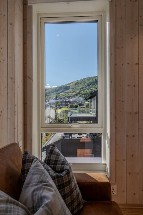 A room with a large window offering a view of a hillside and buildings.