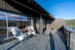 A modern outdoor seating area with two chairs and a table, overlooking a scenic landscape.