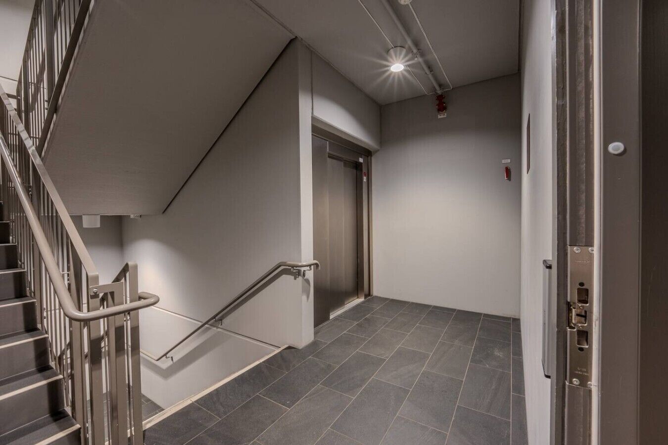 A modern interior with a staircase, elevator, and a door.