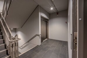 A modern interior with a staircase, elevator, and a door.