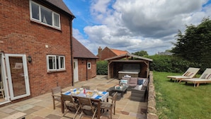 A patio with a table set for a meal, outdoor seating, and a barbecue area. - Bridestones 21 Eskdaleside (Whitby)
