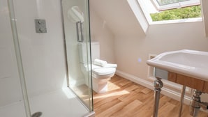 A modern bathroom with a glass shower enclosure, a toilet, and a sink with a wooden countertop. - Bridestones 21 Eskdaleside (Whitby)