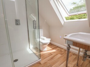 Ein modernes Badezimmer mit Duschkabine aus Glas, Toilette und Waschbecken mit Holzablage.