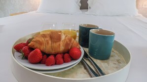 A breakfast setup with croissants, strawberries, raspberries, and juice on a tray, with a bed and pillows in the background. - Bridestones 21 Eskdaleside (Whitby)