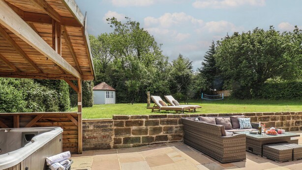 A patio with stone flooring, a hot tub, and outdoor furniture. - Bridestones 21 Eskdaleside (Whitby)