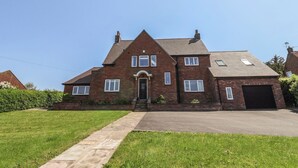 A two-story brick house with a front entrance, a garage, and a well-maintained lawn. - Bridestones 21 Eskdaleside (Whitby)