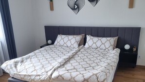A double bed with a patterned bedspread, a dark headboard, and a bedside table with a spherical object. - Apartment 'Weitblick' with Mountain View, Balcony, and Wi-Fi (Reute)