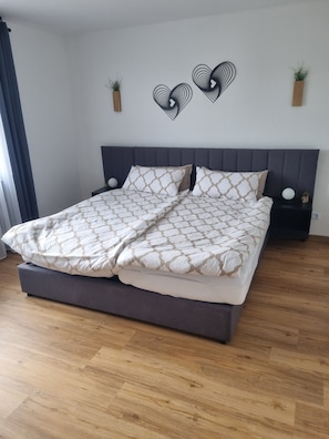 A double bed with a patterned bedspread, a dark headboard, and a bedside table with a spherical object. - Apartment 'Weitblick' with Mountain View, Balcony, and Wi-Fi (Reute)