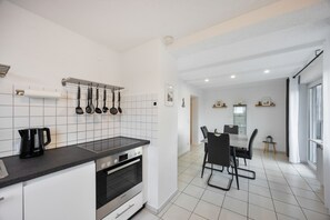 Cozinha moderna com forno Bosch, cafeteira e um suporte suspenso para utensílios.