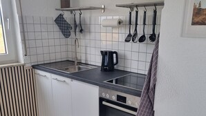 A modern kitchen with white cabinets, a Bosch oven, a sink, and a kettle. - Apartment 'Weitblick' with Mountain View, Balcony, and Wi-Fi (Reute)